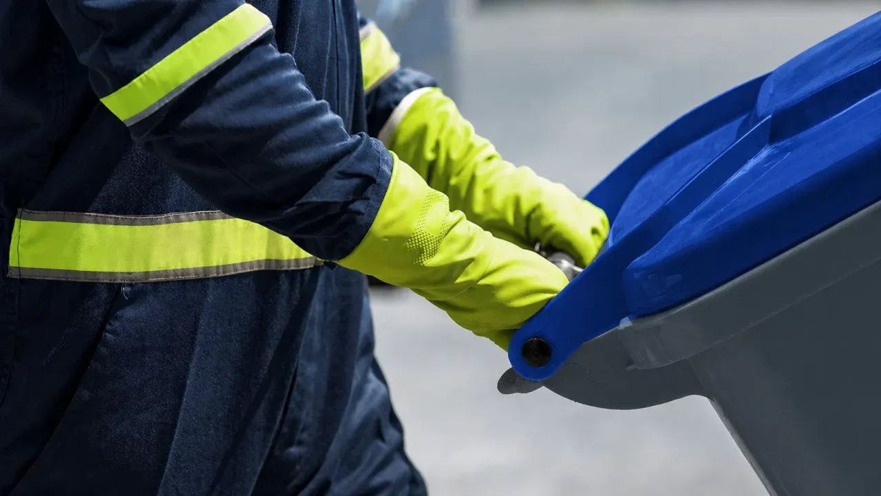 NEW Disposal team member rolling out a recycling cart on a residential driveway